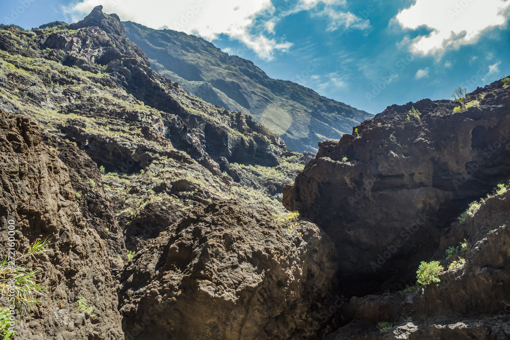 Fototapeta premium Rocks in the Masca gorge, Tenerife, showing solidified volcanic lava flow layers and arch formation. The ravine or barranco leads down to the ocean from a 900m altitude.