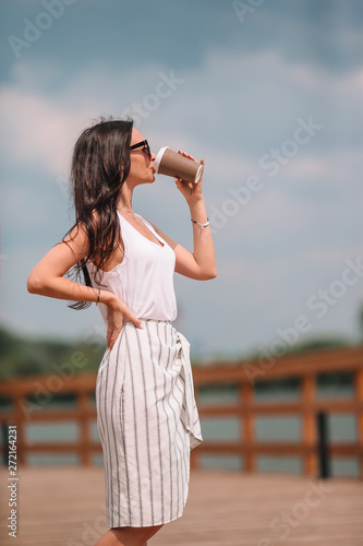 Happy young urban woman drinking coffee in european city.