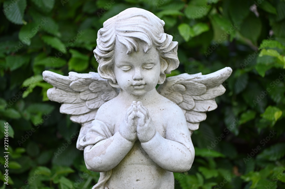A white sandstone sculpture of a praying angel. A white sandstone sculpture of a praying angel.