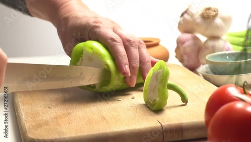 Cutting a green pepper on the wooden board side view