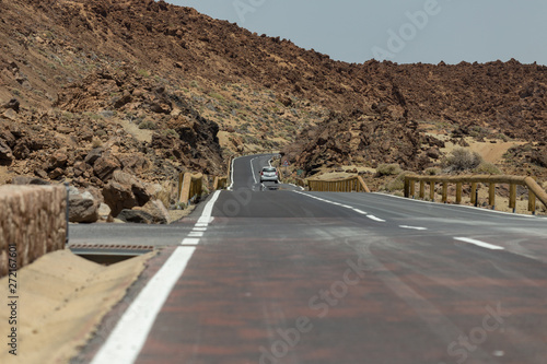 Nearest future. Asfalt road crossing Mars landskape. Mountains around volcano Teide. Bright blue sky. Teide National Park, Tenerife, Canary Islands, Spain.