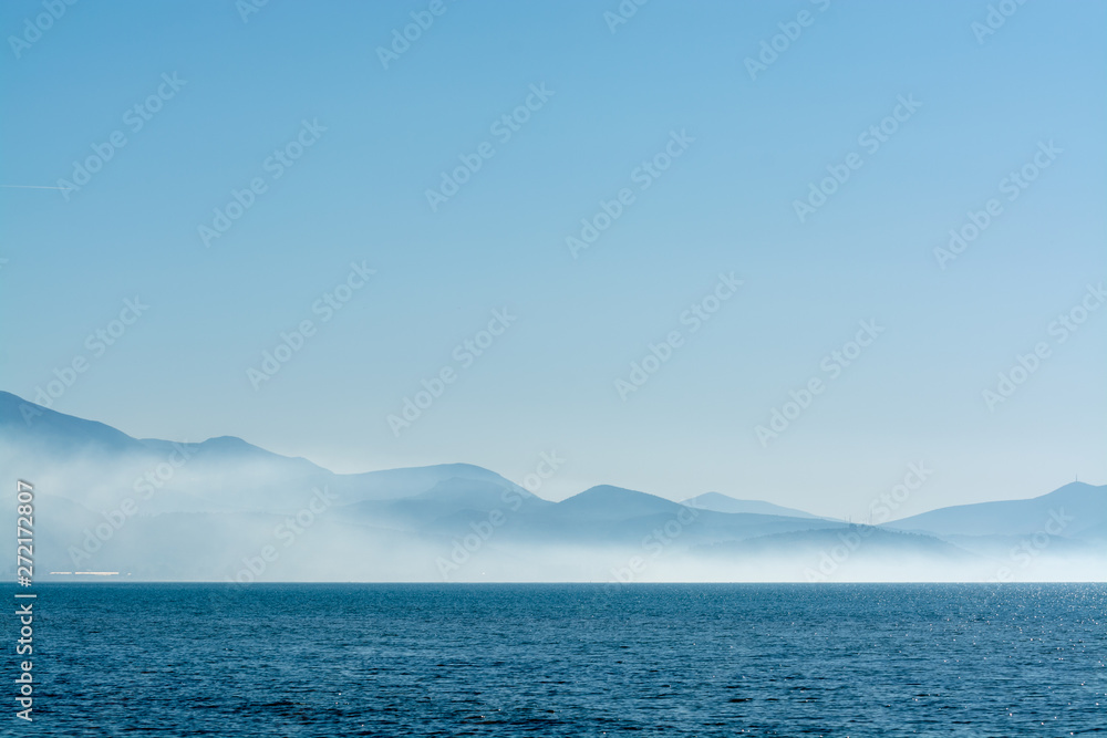 Seascape with low fog clouds over sea water in early morning with sun lights Seascape with low fog clouds over sea water in early morning with sun lights