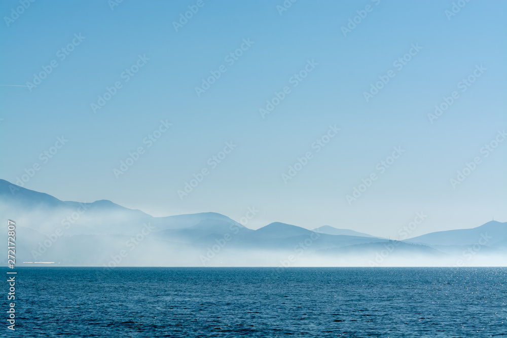 Seascape with low fog clouds over sea water in early morning with sun lights