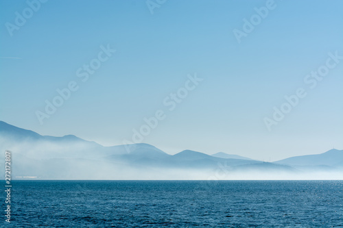 Seascape with low fog clouds over sea water in early morning with sun lights