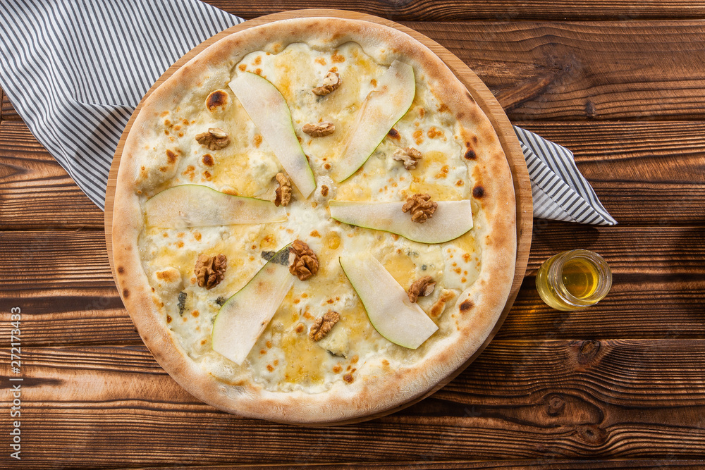 Traditional pizza with pear, nuts and blue cheese on a wooden background. Close up. Top view.