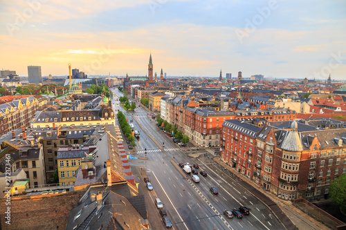Copenhagen, Denmark cityscape at sunrise after rain - skyline with H.C. Andersen boulevard  in the foreground and City Hall clock tower in the distance, under blue and orange sky early in the morning.