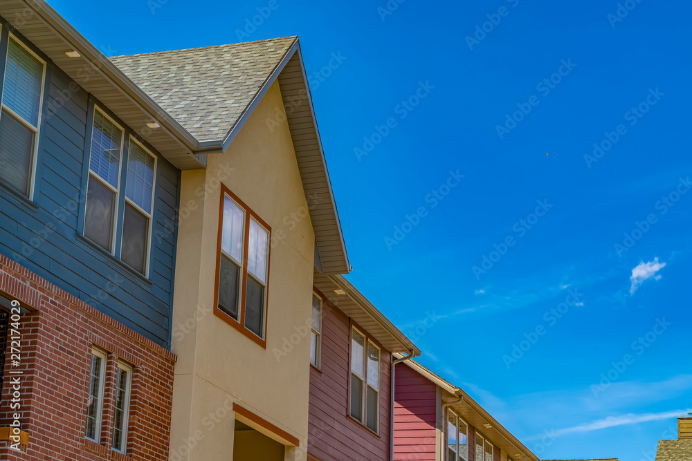 Exterior view of houses against blue sky with wispy clouds on a sunny day