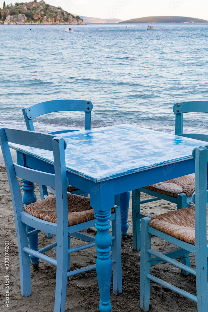 Traditional greek tavern with wooden tables on sandy beach near water waiting for tourists in Tolo, Peloponnese, Greece Traditional greek tavern with wooden tables on sandy beach near water waiting for tourists in Tolo, Peloponnese, Greece