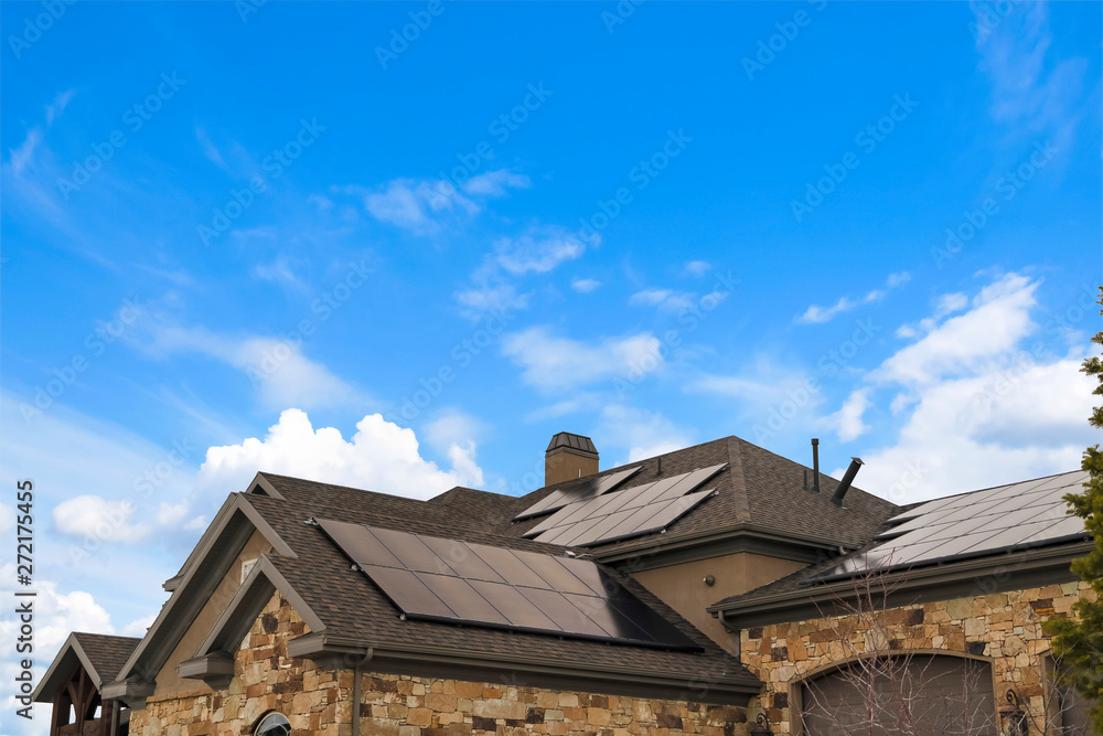 Cloudy blue sky over a home with solar panels on the pitched roof - obrazy, fototapety, plakaty 