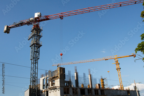 Two Construction cranes tower on blue sky background. Crane and building working progress. Empty Space for text.