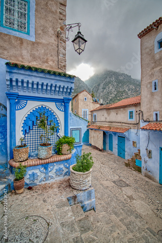 Public fountain on a street in Chefchaouen. In the background we see the mountains and a dramatic sky © juanorihuela