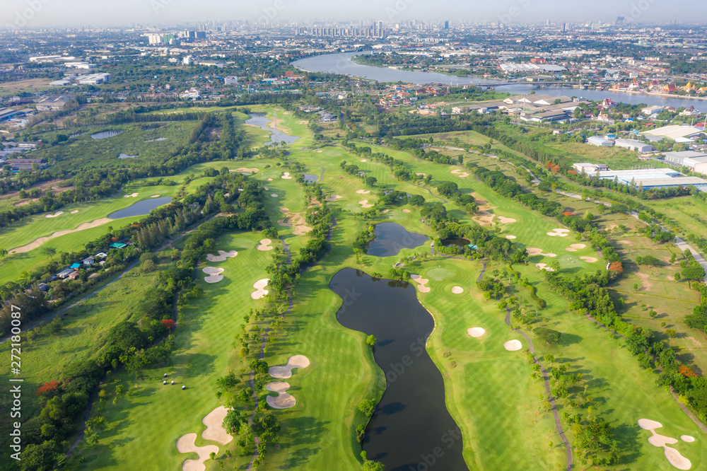 Aerial panoramic view of golf course and houses in city.