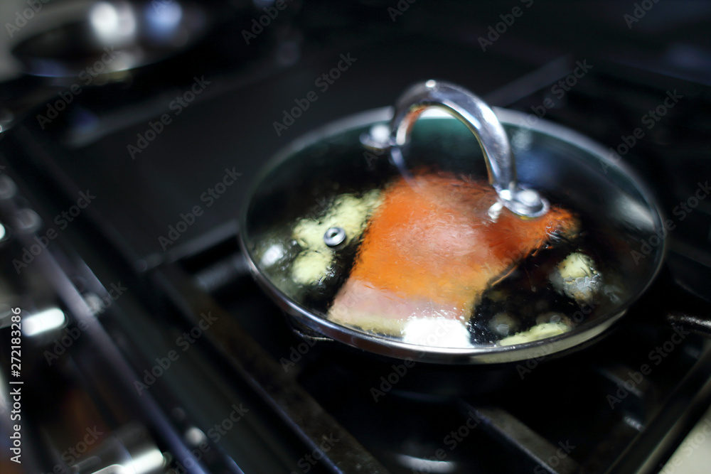 Wild caught King salmon frying in a pan with the skin side down. Stock