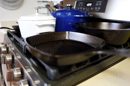 Collection of cast iron cookware on the stove top in a home kitchen.