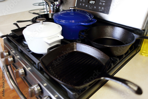 Collection of cast iron cookware on the stove top in a home kitchen.