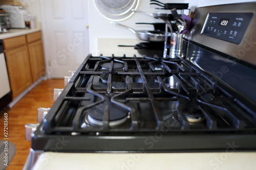 Empty natural gas stove top with cast iron grates, inside a home kitchen.