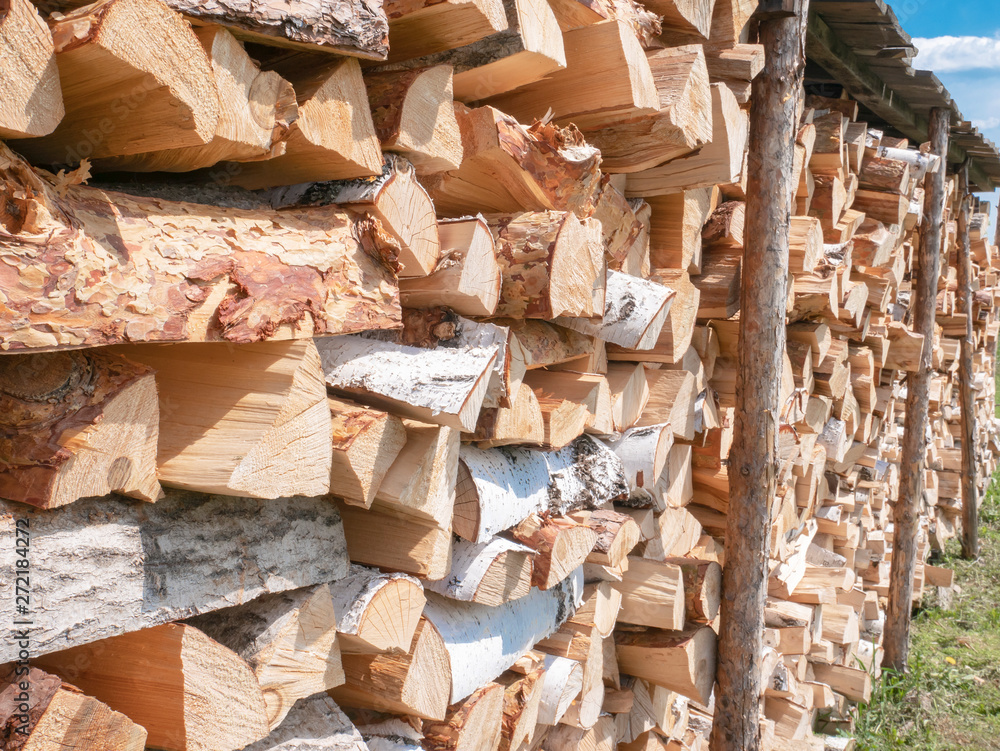 Firewood stacked in a woodpile under a canopy in the open air Firewood stacked in a woodpile under a canopy in the open air