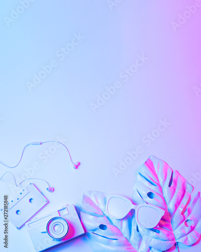 Summer Background, Summer holiday concept, Travel Concept with bag, camera and sunglasses on blue and magenta background. Summertime glowing neon retrowave © Bugaev