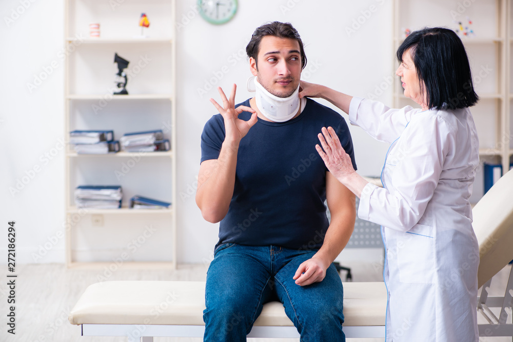 Young male patient visiting aged female doctor Young male patient visiting aged female doctor