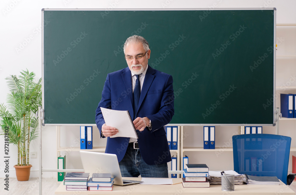Aged male teacher in front of chalkboard Aged male teacher in front of chalkboard