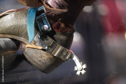 A close up of a cowboy boot and spur on a pipe. photo