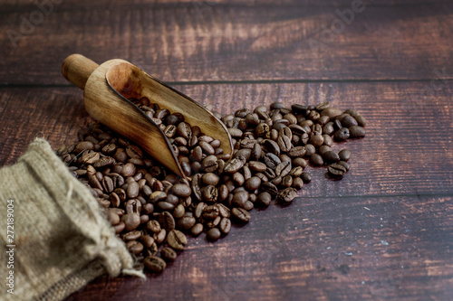 coffee beans roasted in a sack with scoop on wood table background