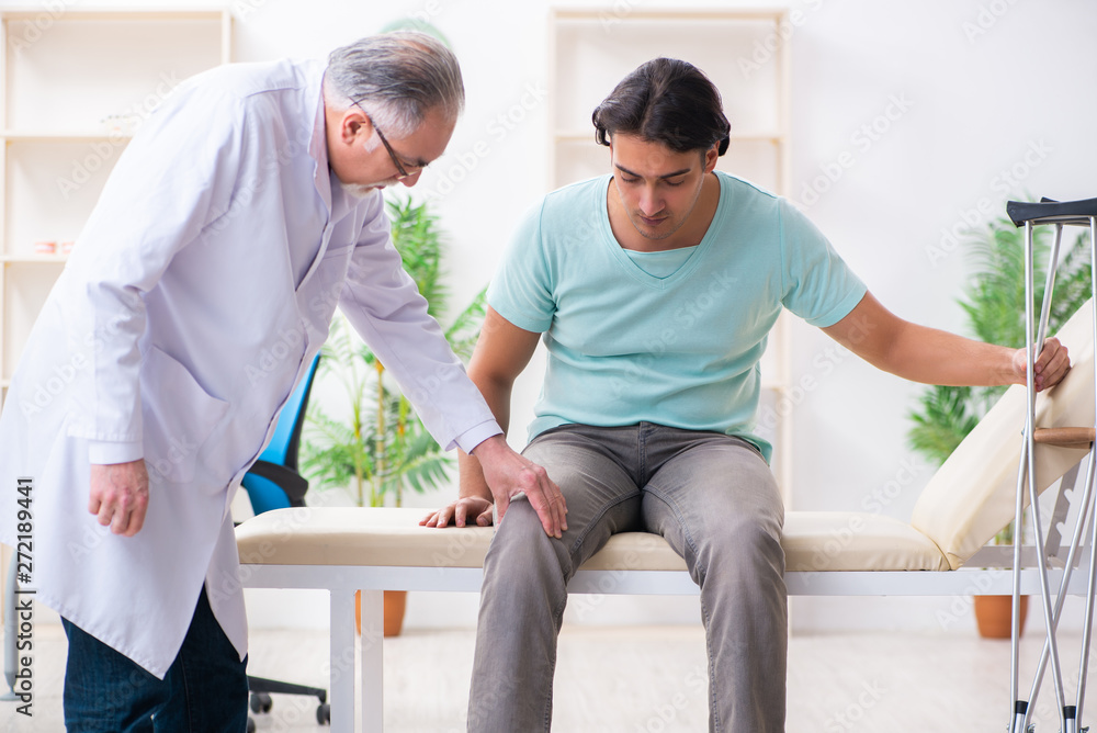 Obraz premium Young leg injured male patient visiting old doctor 
