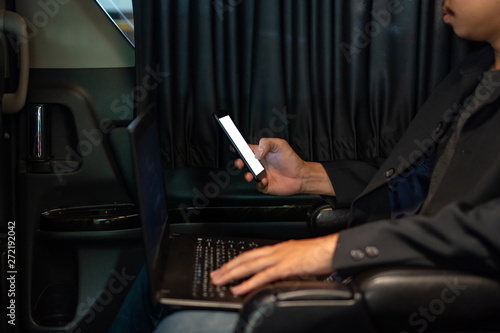 Young businessman using mobile phone and laptop in car