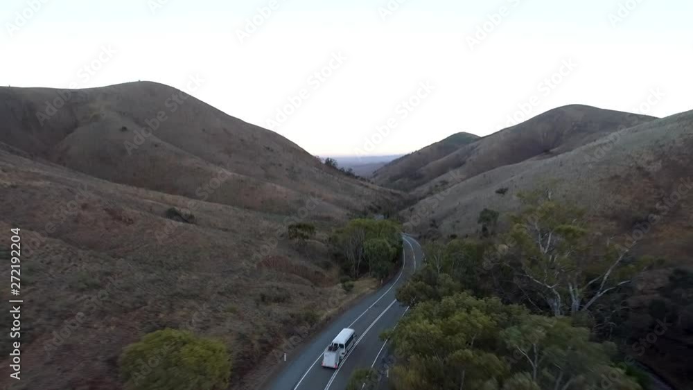 Aerial Forward/Pan Down: White Bus Driving Down Road Surrounded By Dirt Hills - Uluru, Australia Aerial Forward/Pan Down: White Bus Driving Down Road Surrounded By Dirt Hills - Uluru, Australia