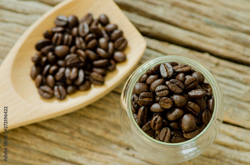 Fototapeta premium Top view of coffee seed in the wooden spoon and glass