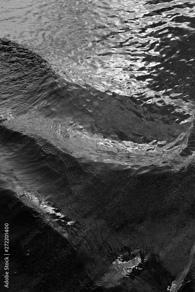 Monochrome abstract water background of small diagonal waves on the ocean’s surface.