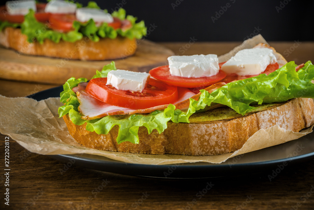 Delicious sandwiches on wooden table with dark background.