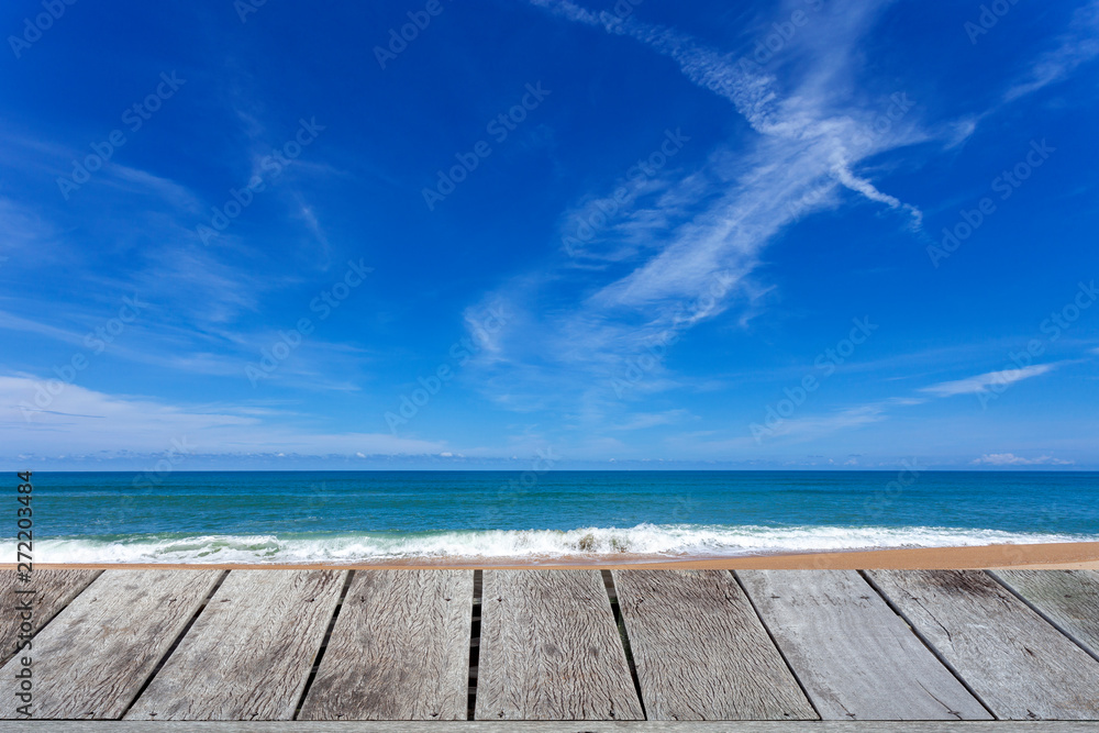 Wooden floor with beautiful blue sky over tropical sandy beach scenery for background
