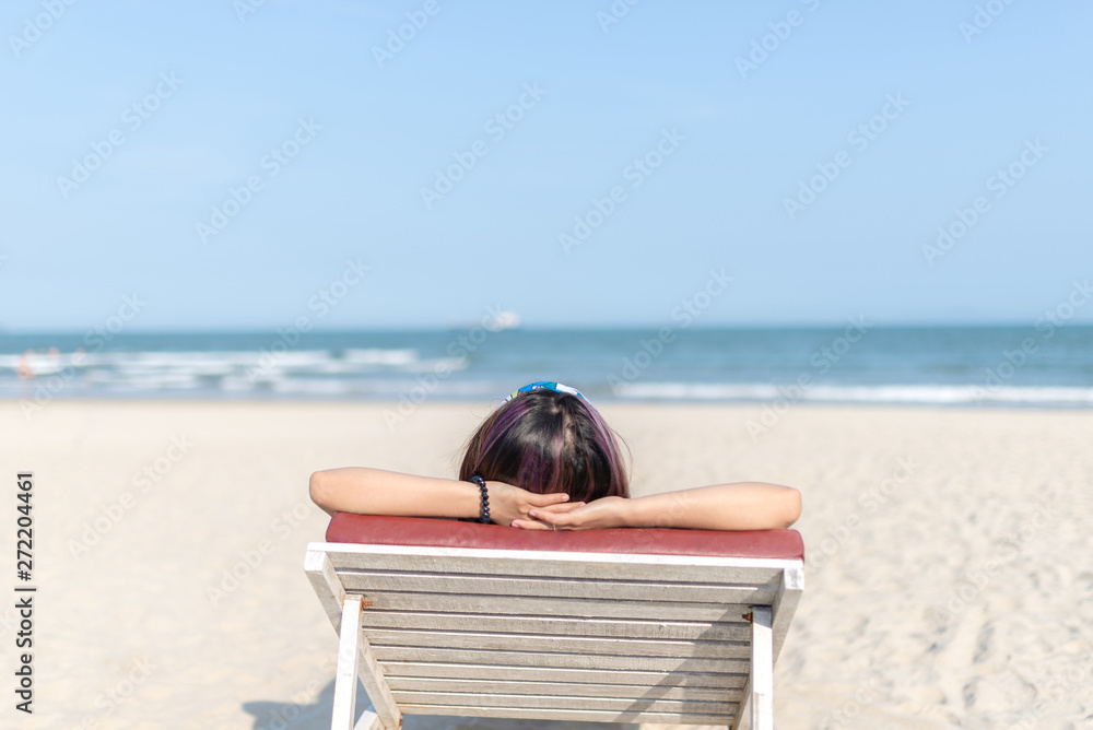 Woman relaxing lying on beach chair arms up on head Woman relaxing lying on beach chair arms up on head