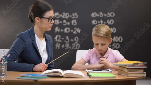 Strict teacher hitting schoolboy with ruler, corporal punishment, breaking rule