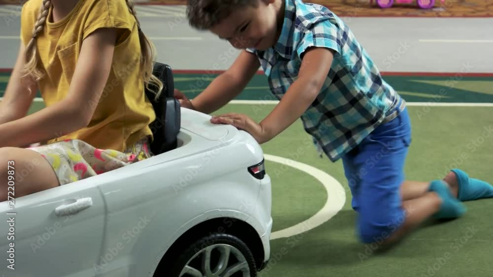 Little boy pushing toy car indoor. Two happy kids playing with toy car. Time together in entertainment center. Little boy pushing toy car indoor. Two happy kids playing with toy car. Time together in entertainment center.