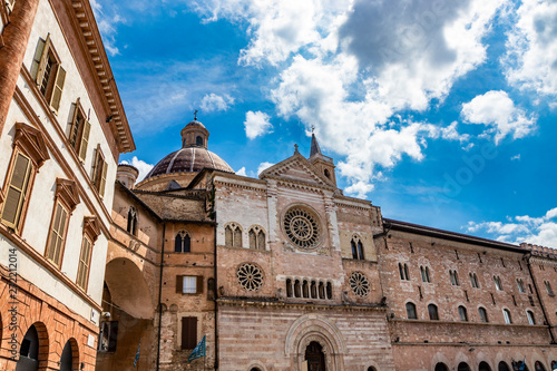 The Cathedral of San Feliciano in the square of Foligno. The side facade, with 3 rosettes, mullioned windows, arches and columns. The bell tower, the dome and the wooden portal. Perugia, Umbria, Italy photo