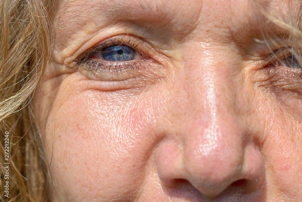 Single blue eye and nose of a middle-aged woman Single blue eye and nose of a middle-aged woman
