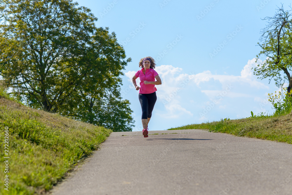 Mature athletic woman jogging on a rural road