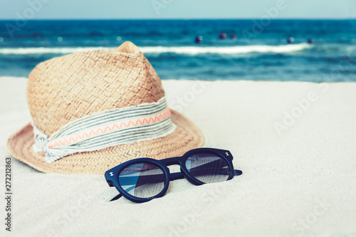 Vintage wicker straw hat and black sun glasses on a tropical beach, summer concept .