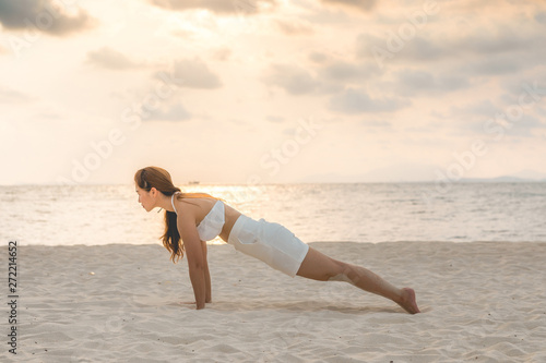 Asian young woman practice yoga Plank or Phalakasana Pose on the sand and beach with sunset beautiful sea in Tropical island,Feeling comfortable and relax in holiday,Vacations Yoga Concept