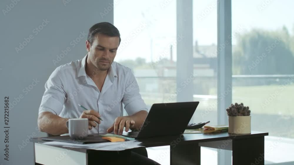 Business man working at laptop computer. Calm man making notes at workplace. Business man working at laptop computer. Calm man making notes at workplace.