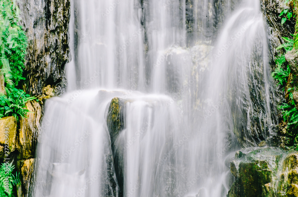 Fototapeta premium A close up view of cascading water falling over the rocks at Longshan Buddhist temple in Taipei city, Taiwan.