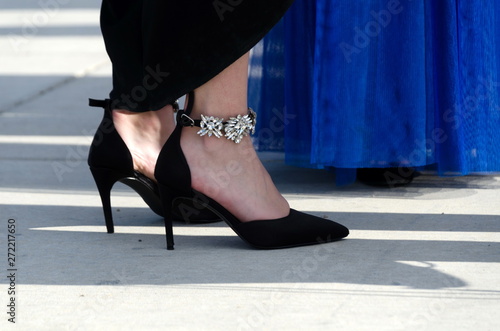 Close-up on high heels of black shoes next to a blue dress
