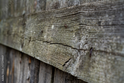 Background from a part of the fence of wooden planks at an acute angle with a low depth of field