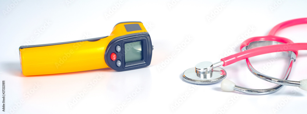 Yellow Infrared thermometer gun used to measure temperature with stethtoscope on white background. Yellow Infrared thermometer gun used to measure temperature with stethtoscope on white background.