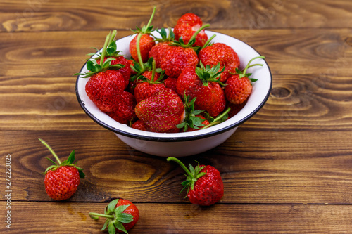 Fresh ripe strawberry in white bowl on a wooden table