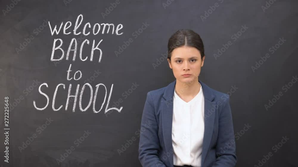 Nervous teacher looking to camera standing near board, welcome back to school Nervous teacher looking to camera standing near board, welcome back to school