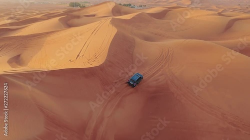 AERIAL. Hight flight above car. Desert safari car sand dunning in the Dubai desert during sunset photo