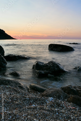 blurry sea long shutter. sunset in the sea with black rocks in the front